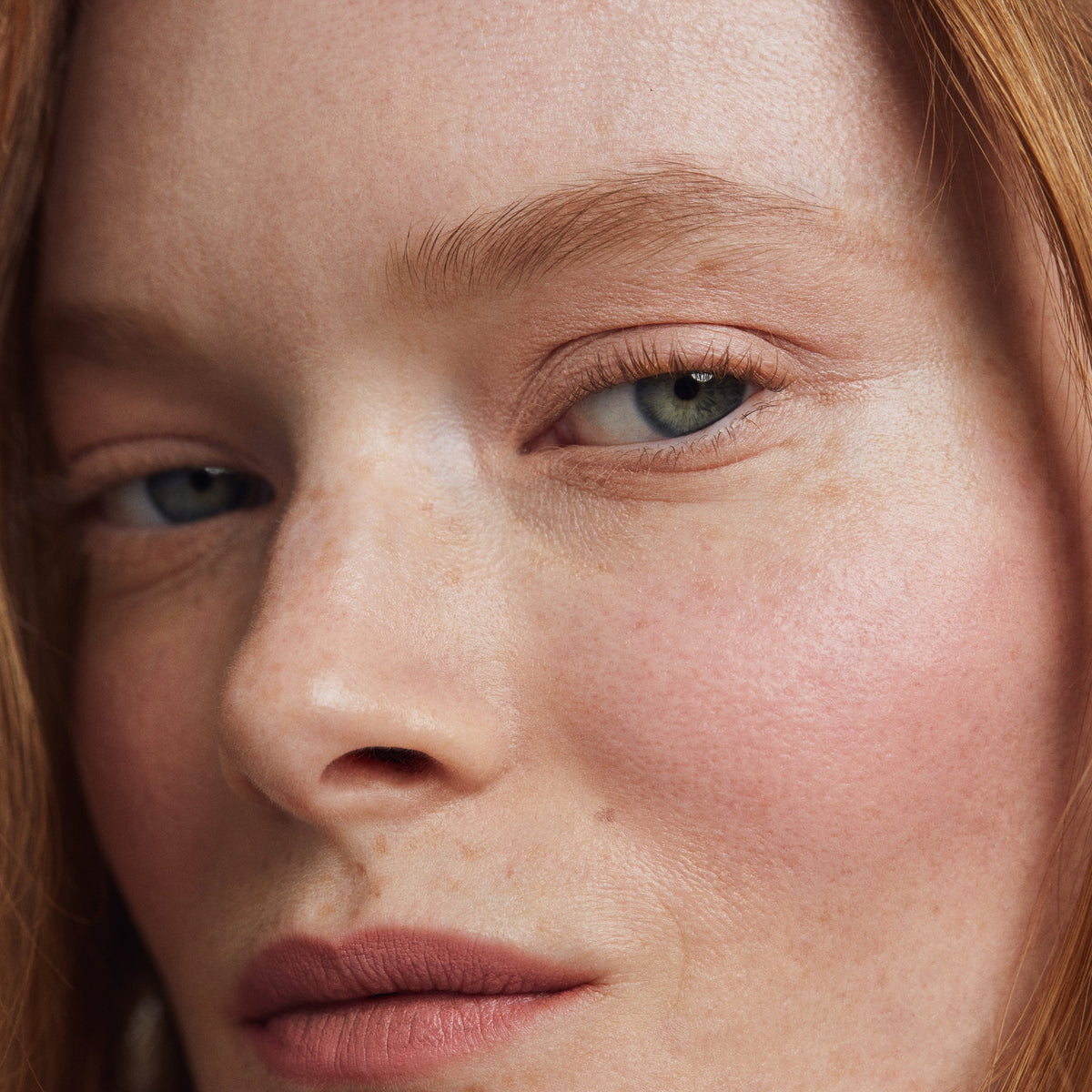 Close up of a person’s face with a fair skin tone, wearing cream blush