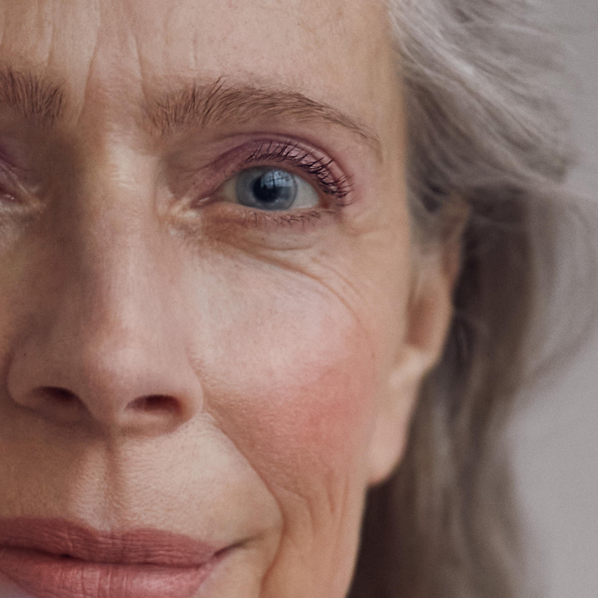 Close up of a person’s face wearing a pink blush