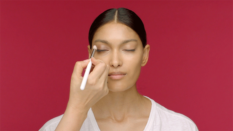 Model applying the Kjaer Weis Cream Eye Shadow, using the Cream Eye Shadow Brush