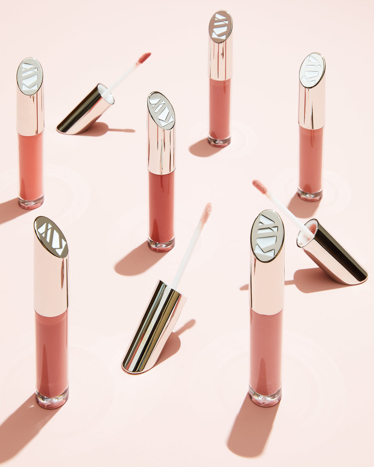 Lip gloss with applicators on a pink background