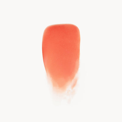 Close-up of a coral-colored lip gloss swatch on a white background