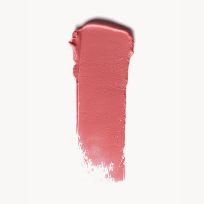 A wipe of warm pink cream blush on a white background